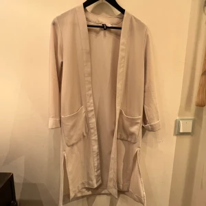 Beige tunn kappa  - Ljusbeige tunn kappa köpt på HM. Luftig och skön att ha på sig.