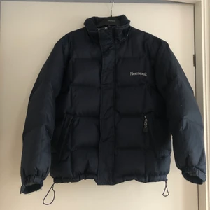Northpeak pufferjacket / dunjacka - Så snygg och skön mörkblå pufferjacket från märket Northpeak. Den är i okej skick, har lite slitningar delvis på luvan (som är avtagbar), saknar dragkedje-hållaren (den man drar i) på högra fickan och den har börjat läcka lite dun. Därav priset. Men jackan går fortfarande att använda utmärkt!:) skriv om ni har frågor eller vill ha bild av något slag!  