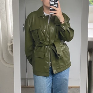 Mossgrön höstjackan från HM - En jacka från HM i nyskick. Användes 1 gång förra hösten, var supercool och passar bra i höstkylan. Materialet liknar skinn men är väldigt mjukt. Stora fickor och med ett band runt midjan som är valfritt. För referens är jag är 1,73 cm lång, har 40 i byxor och s/m topp✨