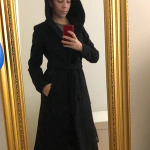 Svart höstkappa Small (storlek 32) - Tjock lång höstkappa med stor luva, två stora fickor plus innerficka. Knappar & knyt runt midjan. Sparsamt använd. Används inte längre och den söker därför nytt hem. 