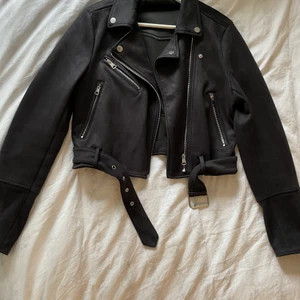 Höst/vårjacka i mockaimitation - Snygg höst-och vårjacka i mörkblå mockaimitation. Lite croppad i modellen och med extra långa ärmar. Endast använd ett par gånger och säljes pga att den inte används längre - alltså som i nyskick!