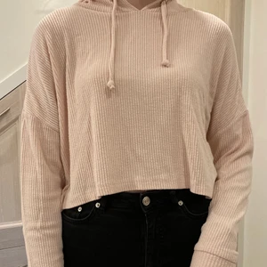 Croppad hoodie - Croppad, ribbstickad, rosa hoodie. Passar både till träningen, till vardags och som myskläder. Säljer därför att den inte är min stil, använd ett fåtal gånger. Mjuk och gosig