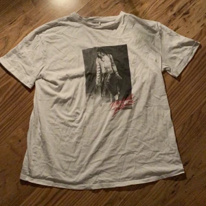 T-shirt - Vit tröja med Michael Jackson tryck och text. Liten skada på ärmen (se bild 2) annars fint skick. Kan skicka fler bilder om det behövs. Frakt ingår i priset!
