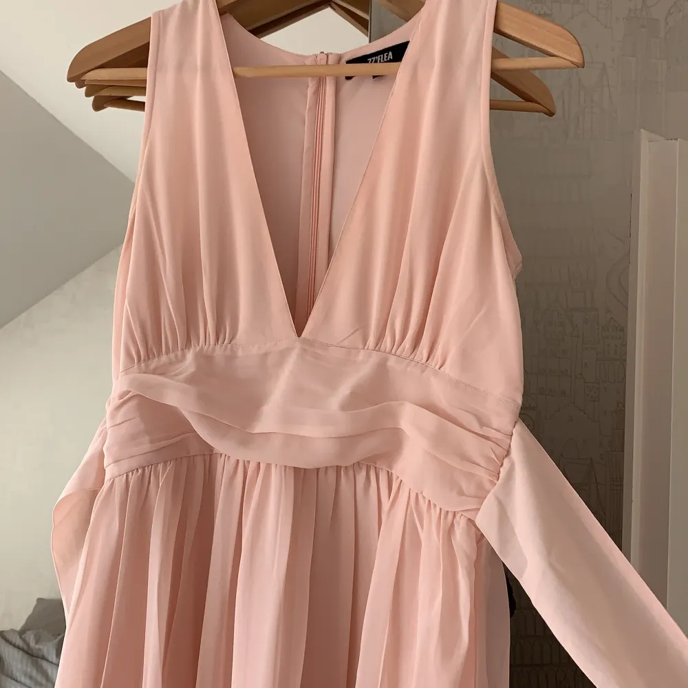 En ljusrosa balklänning från Nelly som är v-ringad, möjlighet att göra en rosett i ryggen samt en underklänning i klänningen som gör att den inte blir genomskinlig!. Klänningar.