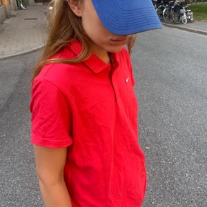 En fräsch röd Nike pikétröja - En jättehärlig pikétröja som går att använda på både sommaren och för att lattja upp vintern lite. Den är i bra skick. Den är av märket Nike. Storleken är Xl men hon på bilden har storlek S så det beror lite på hur man vill ha den. Köparen står för frakt.