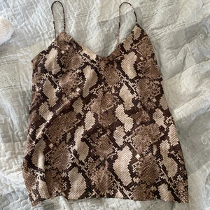 Linne från hm - Ormmönstrat linne från h&m som aldrig används! Dubbla tyg fram vid bysten och uppe där bak (syns på 2 bilden). Storlek 40 men passar 36-40 beroende på hur man vill att de ska sitta. Pris + 45kr frakt 🦋