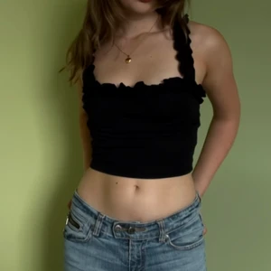 Svart romantiskt linne  - Ett svart linne med axelband som har volanger. Linnet är i perfekt skick och upplevs vara i storlek s-xs.              Frakt: 70 kr om inte möjlighet finns att mötas upp.