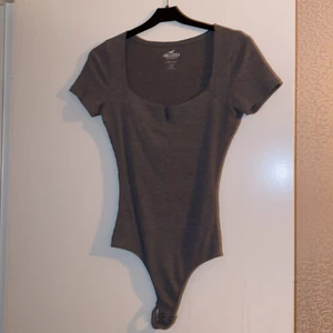 Hollister - Skit snygg grå body använd ett få tal gånger, de är string där bak, perfekt till när man ska ha byxor över;) Den är i storlek S💖🌺