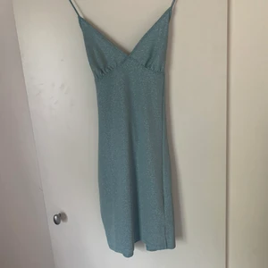 Blå glittrig klänning med slits - Oanvänd klänning storlek S, lapparna kvar. Säljes för 100kr inkl frakt