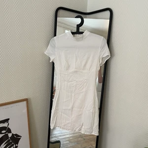 Vit klänning  - Vit klänning i sidenimitation, kort med en liten slit på ena sidan!