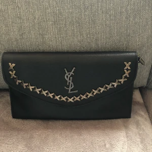 Ysl - Ysl väska som är aldrig använd, finns ett axelband till som ligger i väskan men kan användas som en clutch också. Säljer för 200 och den är ej äkta.