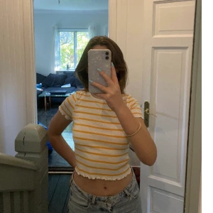 Söt topp från Gina - Söt ribbad topp med fina detaljer på ärmarna och ner på tröjan. Ränderna är gul-orangea. Mycket använd men fortfarande bra skick. Säljer pga att den nt kommer till användning! 💛🧡 stretchigt material så skulle passa S oxå. 