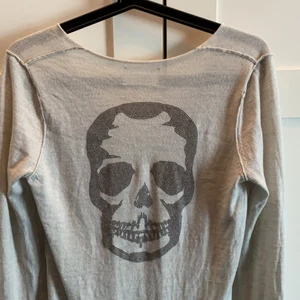 Tunn Kashmir ZADIG tröja - Jättefin, aldrig använd Zadig & Voltaire tröja i tunn Kashmir. Super fin beige färg med döskalle i nitar på ryggen. Perfekt på sommaren med en kjol, eller med ett par slitna jeans för en lite coolare look. Går ej att köpa längre (köpt för 3600) 