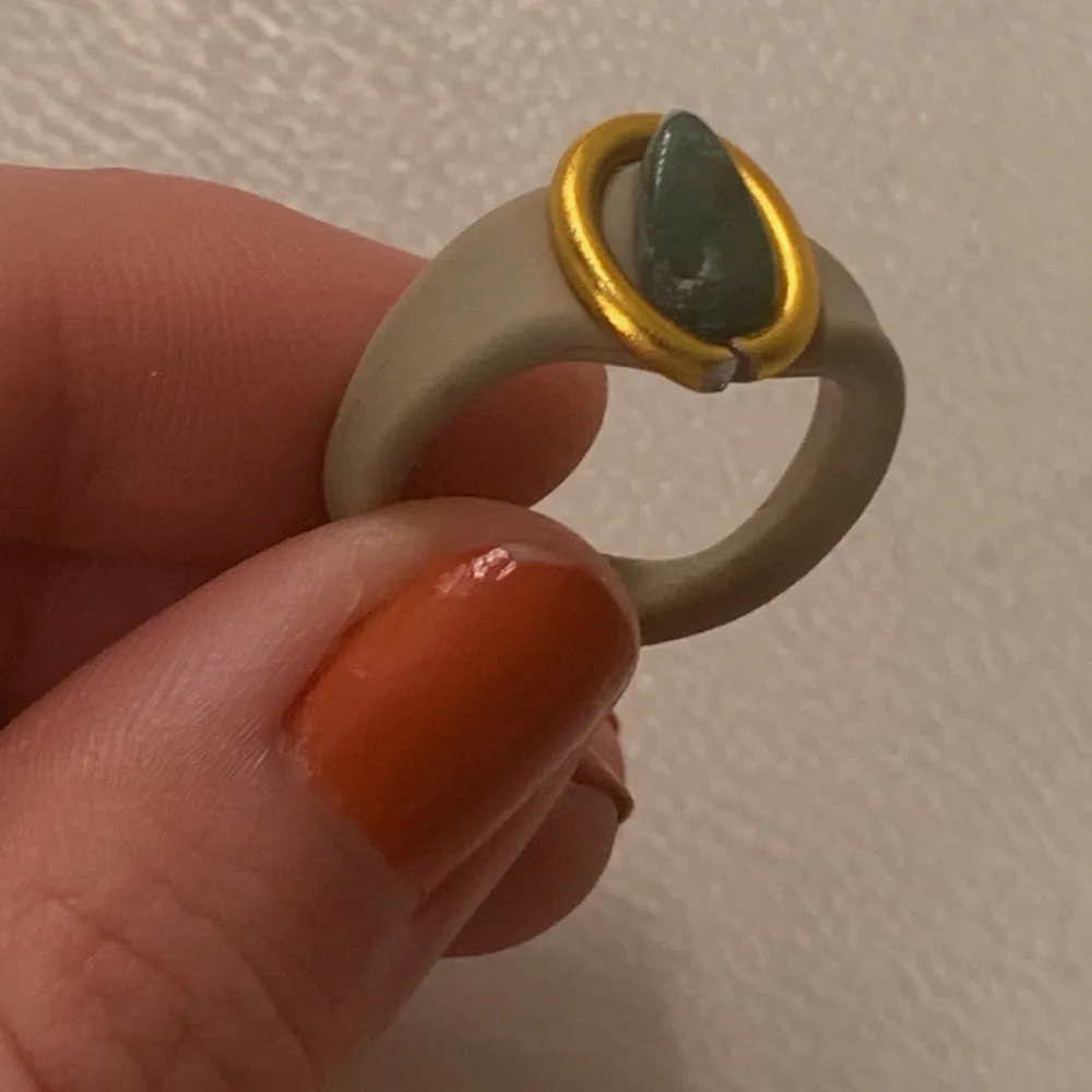 En ring av beige lera med guldig ståltråd och en liten grön kristall! Kristallen är äkta, det är grön aventurin!✨. Accessoarer.