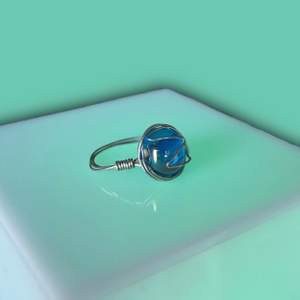 En ring med en blå glaspärla (skiftar lite i lila). Tycker den ser ut som en planet! Säljer för 30kr + 12kr frakt🪐💫