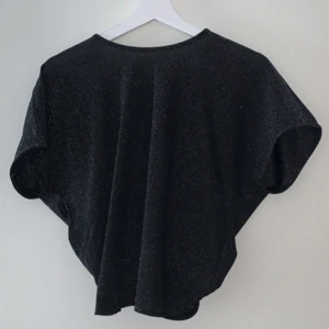 Tröja med öppen rygg - Glittrig topp med knytning i ryggen som sitter riktigt snyggt på. Köparen betalar frakten