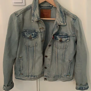 Blå jeansjacka - En blå jeansjacka i storlek L från Levis. Den är liten i storleken för att vara en L. Jag som är en 36 passar perfekt i den. Använd ett få antal gånger, är i jätte bra skick. Den är inte oversized utan en vanlig modell som slutar vid höfterna. Ny pris 500kr, säljer den nu för 200kr+ frakt vid leverans.