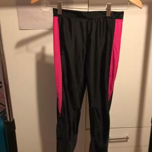 Svarta och rosa träningsbyxor med dragkedja detalj i benen och ficka i baksidan.