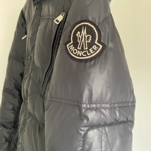 Superbillig Moncler  - Gammal och sliten mörkblå Moncler jacka. Har använts flitigt därav inte bästa skick. Två små hål på vänster baksida - se bild, och uppe i kragen (som dock döljs av luvan) 