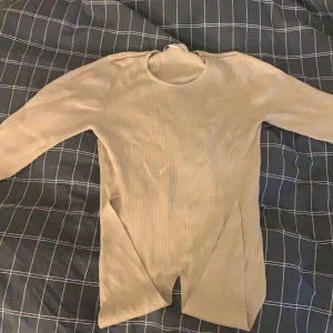 Tröja med knytning - En beige ribbad tröja med knytning fram och lite kortare i armarna