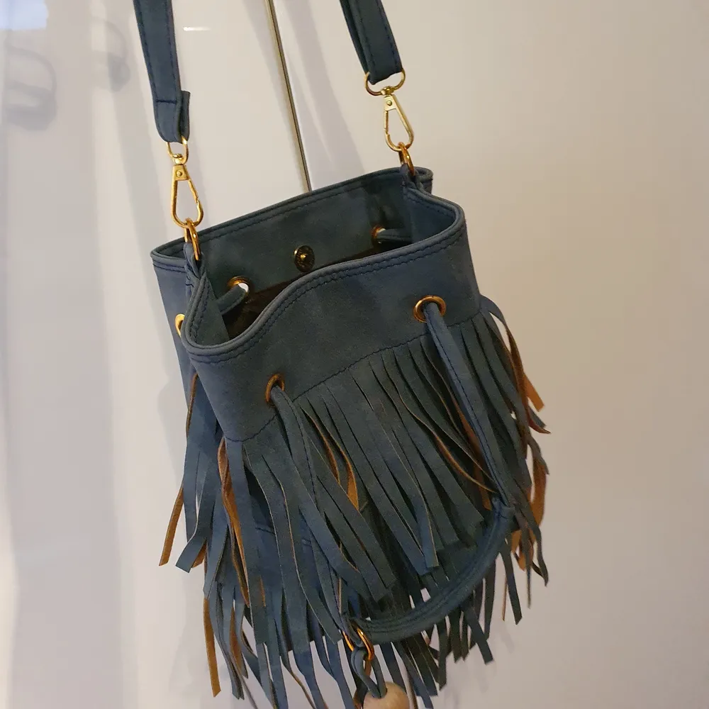 En blå väska med fransar på ena sidan säljes pga använder den inte. Kostar 150 +60 kr frakt.. Väskor.