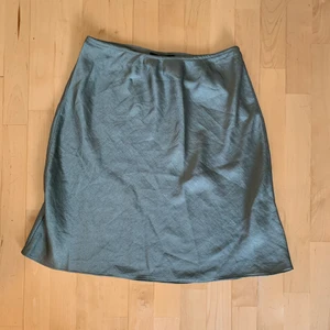Grön satin kjol - En jättefin grön satin kjol, passar perfekt nu till sommar. Köpt förra sommarn men har aldrig använt, så tänkte den kunde komma till användning av någon annan. Den är i modellen Tall, jag är 179cm som referens. (Köparen står för frakten)
