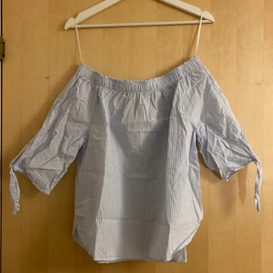 Ljusblå randig blus  - Supersöt ljusblå off the shoulder blus med vita ränder. Köpt på H&M och aldrig använd. Köparen står för frakten 📦