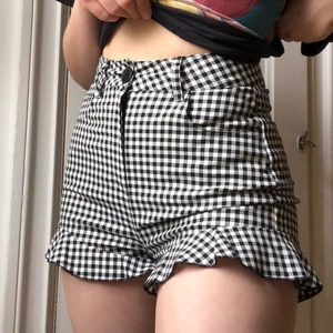 Svart-vit-rutiga shorts med volang - Söta, korta shorts i svart-vit-rutigt mönster med volanger längsmed fållen. Perfekt till sommaren!