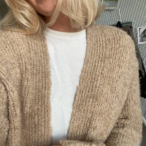 Beige lång kofta - Nyskick! Beige stickad längre kofta som slutar mitt på låren (se bild 3). Fickor på sidorna. Använd 1 gång. Den är inget sticksig alls! 