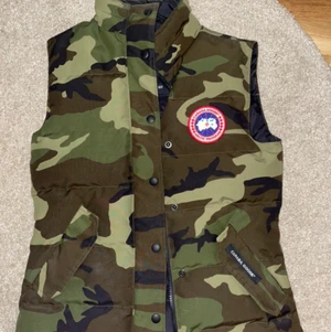 Canada Goose - Säljer denna fina väst ifrån Canada Goose, västen är äkta och köpt i butik. Den är köpt för ca 4000 kr och säljer den för 1000 kr. Västen är i jätte fint skick, inga hål eller fläckar utan västen är som helt ny och i Strl XS😊