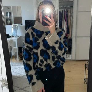 Stickad tröja från Gina tricot - En skön och mysig stickad tröja ifrån ginatricot som är beige med svart&blått leopard mönster. Tröjan är i storlek M, men skulle även kunna passa någon som vanligtvis har S eller L beroende på hur man vill att tröjan ska sitta. Den har även en liten mysig polokrage och armarna är superfina då de är raka nedtill✨