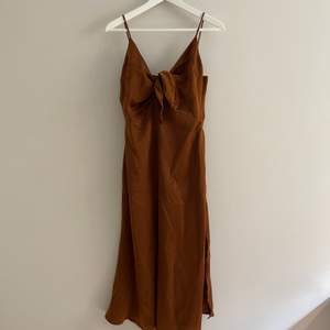 Oanvänd klänning i rostbrun satin. 