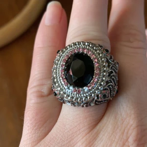 Ring stor o maffig  - Stor maffig ring. Så vacker ring. Har tappat två rosa stenar uppe vid den stora svarta. En liten fläck finns. Se bilder. Frakt 15 kr 