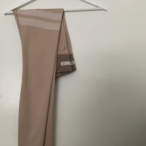 Stronger träningstights - Endast testade beiga Stronger ”Sahara” träningstights i storlek s, hög midja med resår. Midjemått 64 cm. Frakt på ca 50kr tillkommer💓