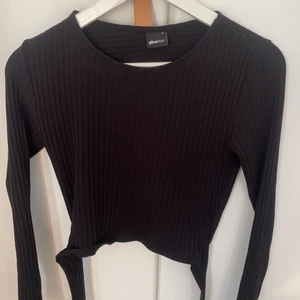 Svart tröja med knytning i ryggen  - En svart långärmad tröja med knytning i ryggen o ribbat material.