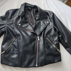Biker Jacka storlek 44 - Kort biker jacka (faux leather) från H&M med silver detaljer. Kroppsformande och lite tight runt armarna om man har muskulär armar (som jag). Jag använde den ett par gånger sen jag köpte den så den är på väldig bra kondition! Vi kan prata igenom priset. Frakt betalas av köparen.