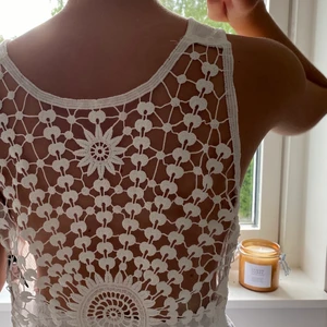 Topp med öppen rygg  - Jag säljer denna vita topp med riktigt fin rygg där man ser broderade detaljer. Man kan även ha ett linne under, själv har jag använt den som ett strandplagg att ha över bikinin.😊