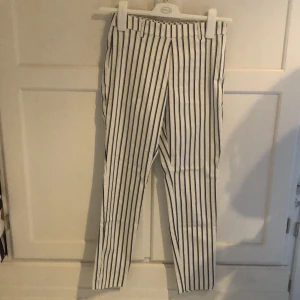 Slacks från Hm storlek 34 - Blå och vit randiga slacks från Hm i storlek Xs. Dragkedja i sidan. Har en liten fläck på benet som man kanske kan få bort själv. Skriv så kan jag skicka bild på den.