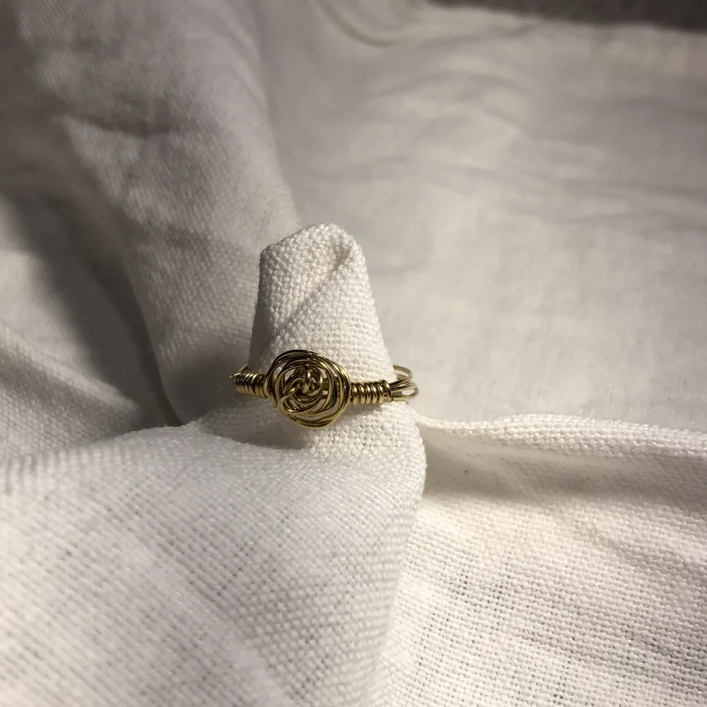 Hemmagjord ring i färgen guld med en liten guldfärgad ros på. Passar bra till vita och beicha kläder. . Accessoarer.
