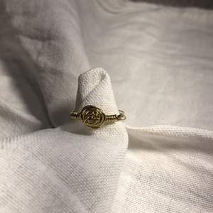 Hemmagjord ring i färgen guld med en liten guldfärgad ros på. Passar bra till vita och beicha kläder. 