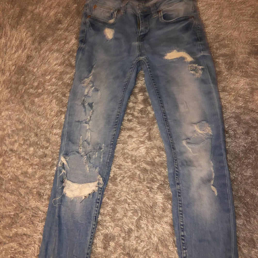 Blåa jeans med stora hål och slitningar . Jeans & Byxor.