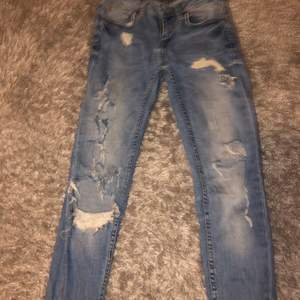 Blåa jeans med stora hål och slitningar 