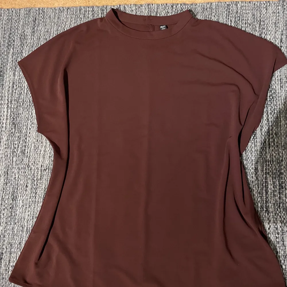 En oversized blus från Uniqlo i choklad färg. Passar perfekt under kavaj eller överskjorta. Storlek XL, men passar mig som använder S/M. Säljer för att jag har två sådana. Längden 65 cm. . Blusar.