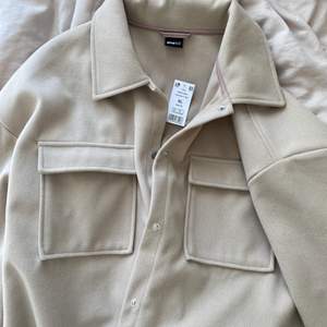 Snyggaste beiga skjortjackan från Gina Tricot, som säljes då den inte kommer till användning. Perfekt nu i höst! Jackan är i storlek XL, men är inte oversize i sig utan skulle säga att den motsvarar en oversize M 💕 Aldrig använd, så prislapp finns kvar! Frakt tillkommer.