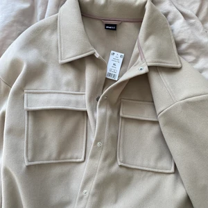 Beige skjortjacka - Snyggaste beiga skjortjackan från Gina Tricot, som säljes då den inte kommer till användning. Perfekt nu i höst! Jackan är i storlek XL, men är inte oversize i sig utan skulle säga att den motsvarar en oversize M 💕 Aldrig använd, så prislapp finns kvar! Frakt tillkommer.