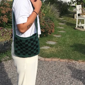 Kuvertväska  - En grön/svart rutig väska som jag själv virkat i återvunnet garn!🍀bandet är tillräckligt långt att både bära på och över axlarna!! Supertrendig och rymlig för sin storlek och sitt ”petit” utseende💗.                                                                                    Tveka inte att skriva om du har fler frågor eller såå!!  Kika även gärna in på min sida där jag säljer mer egensydda och virkade kläder av återvunnet material🌳🌳 Finns även på instagram @lucu.studio 💗💗