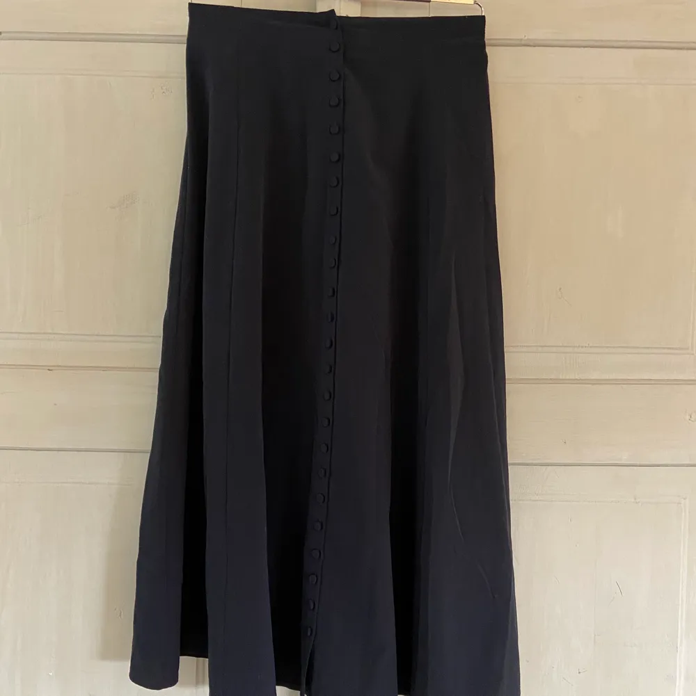 Lång svart kjol med knäppning hela vägen i fram storlek 34. Köpt för två somrar sen och använd under en säsong. Fint skick.. Kjolar.