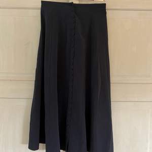 Lång svart kjol med knäppning hela vägen i fram storlek 34. Köpt för två somrar sen och använd under en säsong. Fint skick.
