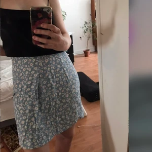 Omlottkjol - Gullig omlottkjol med blommigt motiv 🌸 säljes då den är för stor för mig. Storlek: 3 - mått: runt midjan: 78 cm , Längd: 45 cm. Köpt secondhand. Pris: 80 kr + 66 kr frakt.