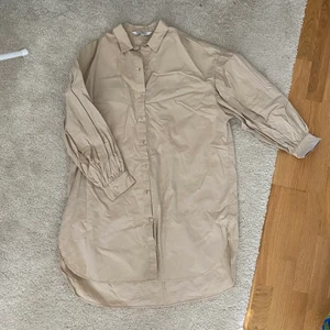 Lång bomullsskjorta - Lång, beige bomullsskjorta som är lite oversized. Använd ett fåtal gånger. I storlek M, men sitter även snyggt på en S som lite mer oversized. Går att använda som klänning om man vill